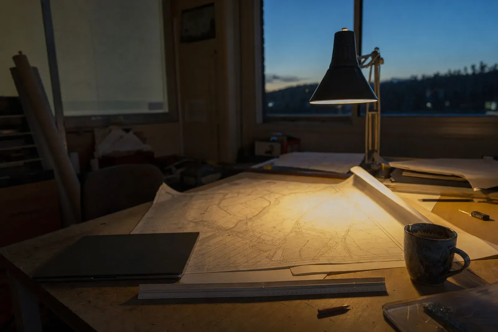 A plat unrolled on a desk at dusk